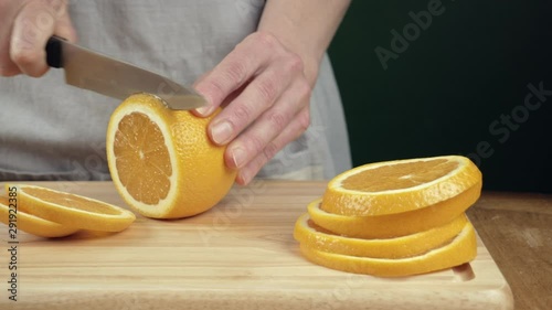 Female hands cut an orange on cutting board. Close up slider movement