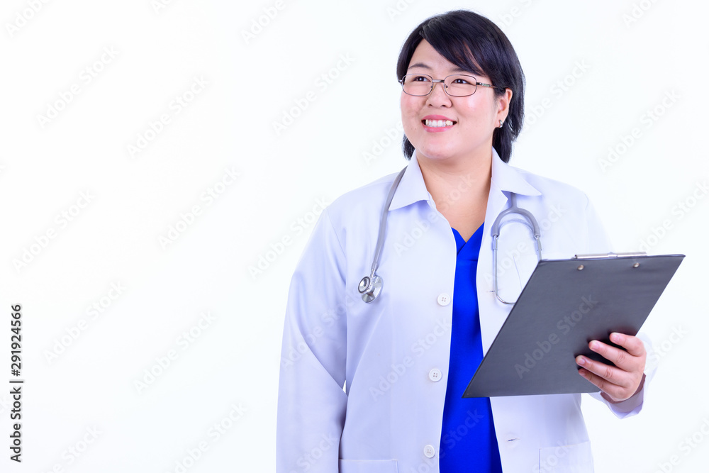 Happy overweight Asian woman doctor thinking while holding clipboard Happy overweight Asian woman doctor thinking while holding clipboard