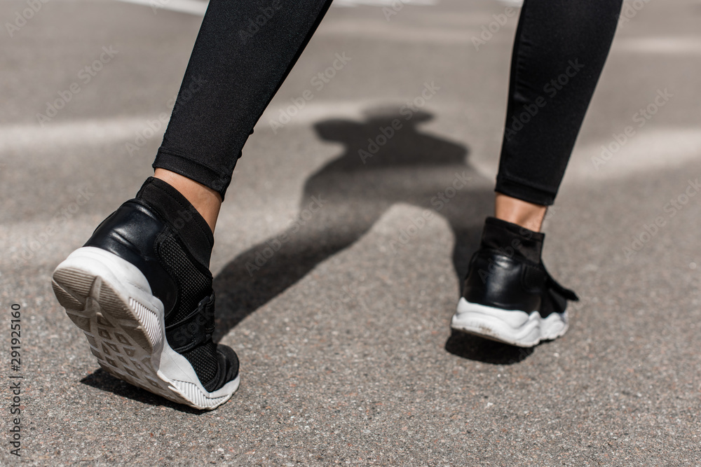 cropped view of sportswoman in black sneakers on street cropped view of sportswoman in black sneakers on street