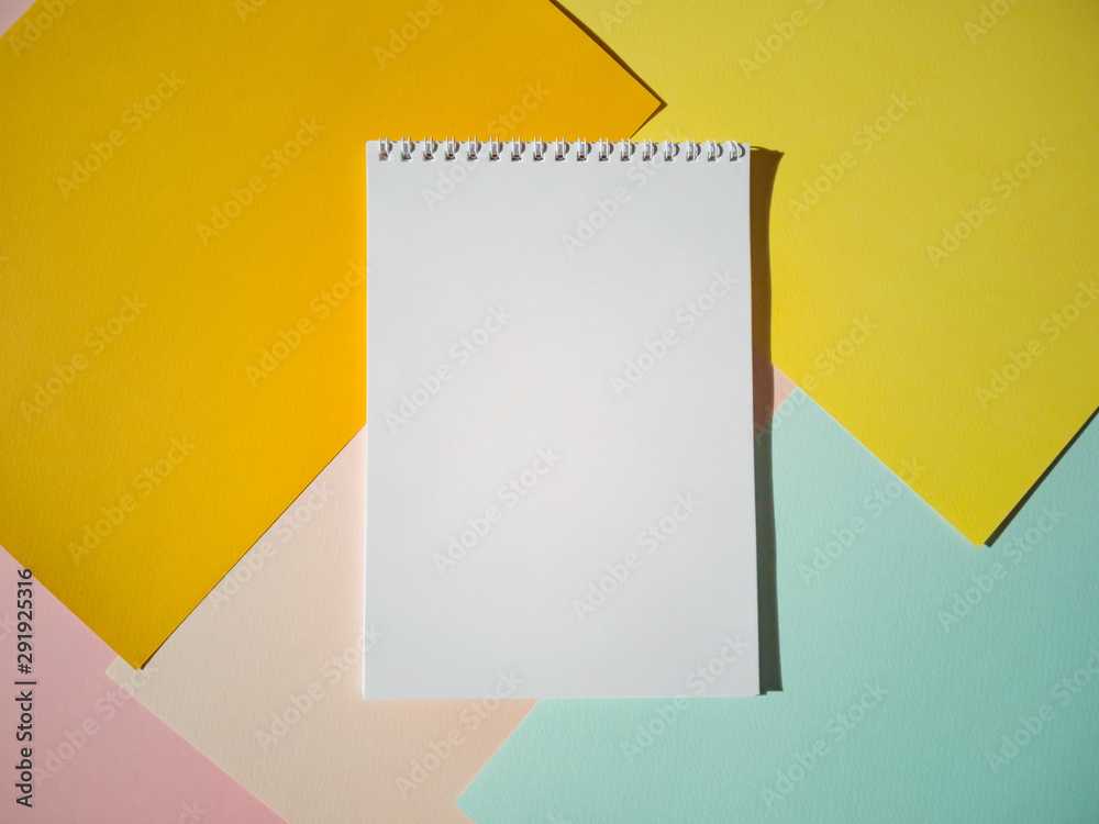 Blank notepad on a spiral with white pages on colored sheets of paper. Top view, minimalism, flat lay. Place for text, copy space. Blank notepad on a spiral with white pages on colored sheets of paper. Top view, minimalism, flat lay. Place for text, copy space.