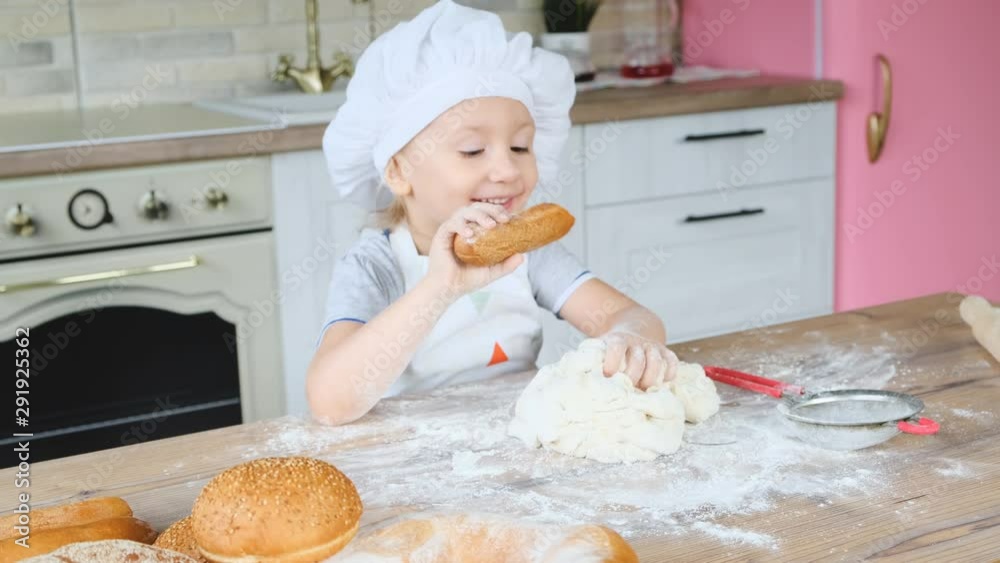 Happy baby girl in the kitchen playing with flour to have fun. A child dressed as a cook. 4K video. Happy baby girl in the kitchen playing with flour to have fun. A child dressed as a cook. 4K video.