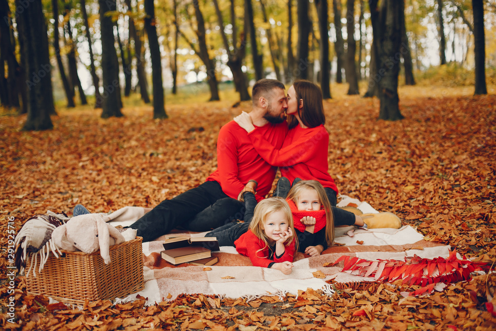 Fototapeta premium Family in a autumn park. Woman in a red sweater. Cute childrens with parents