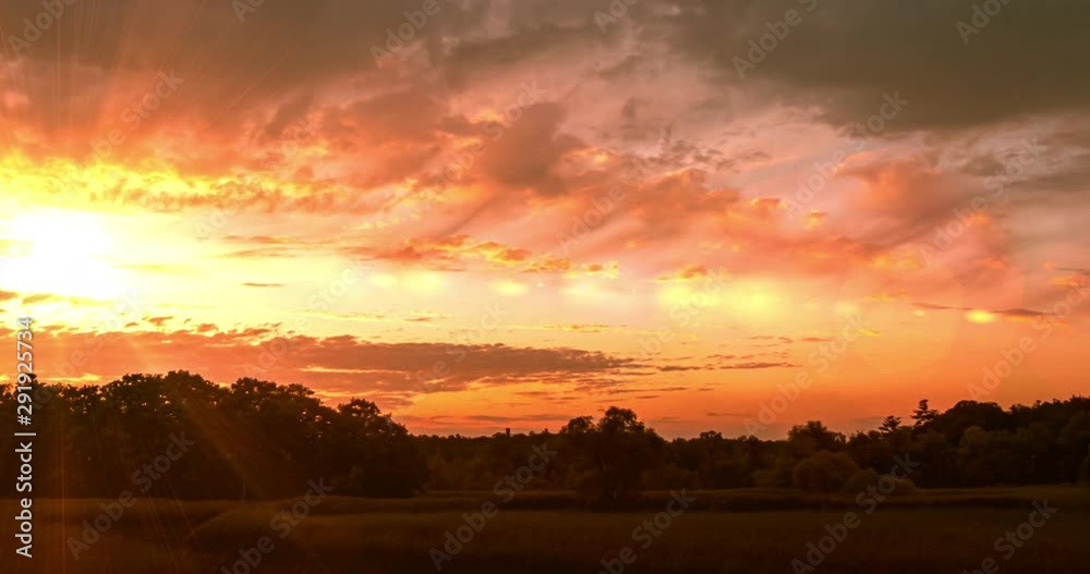 Dramatic Time Lapse Sunset over Storm Clouds. Evening, Large beautiful orange color sunset sky. Red purple orange blue pink. Landscape of Storm clouds moving across the sky against the setting sun.