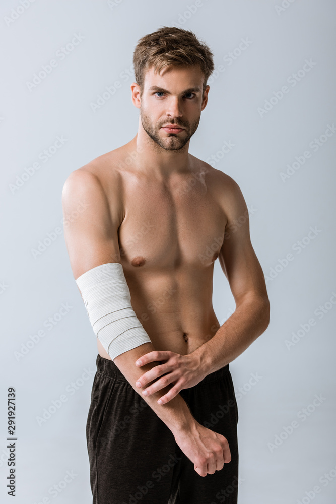 shirtless sportsman with elastic bandage on elbow isolated on grey shirtless sportsman with elastic bandage on elbow isolated on grey