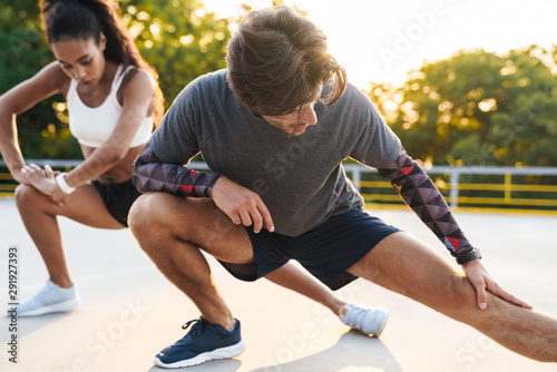 Photo of attractive concentrated couple stretching their legs together