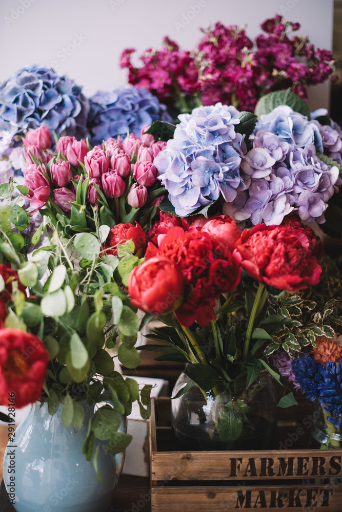 Beautiful fresh flowers at the florist shop: coral peonies, lavender coloured tulips, blue hydrangeas, purple Matthiolas