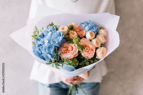 Wallpaper Mural Very nice young woman holding a beautiful blossoming flower bouquet of fresh hydrangea, roses, carnations in pink and light blue colours on the grey wall background  Torontodigital.ca