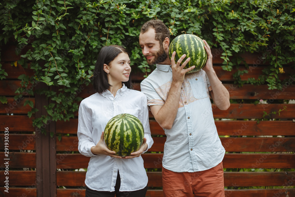 Fototapeta premium Portrait of a smiling couple with a watermelon in their hands. Wooden background.