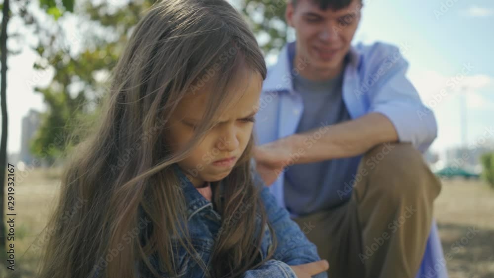 Portrait of childly offended and angry little harm girl on the background of her elder brother in sunny autumn day. Portrait of childly offended and angry little harm girl on the background of her elder brother in sunny autumn day.