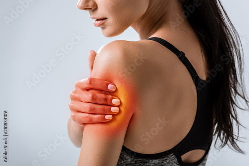 cropped view of sportswoman with arm pain isolated on grey