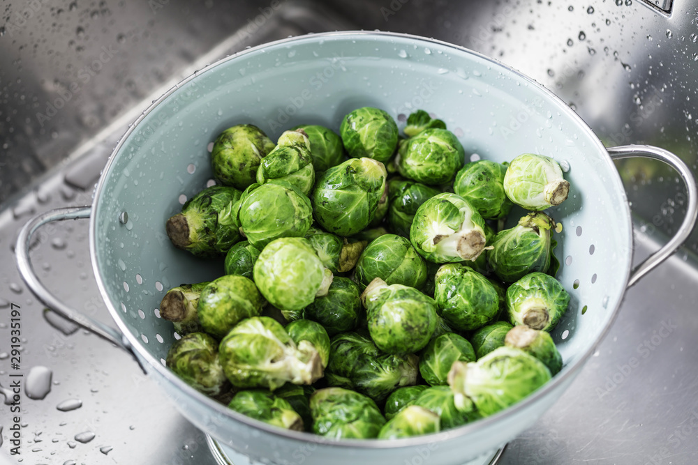 washing raw Brussels sprouts in kitchen sink washing raw Brussels sprouts in kitchen sink