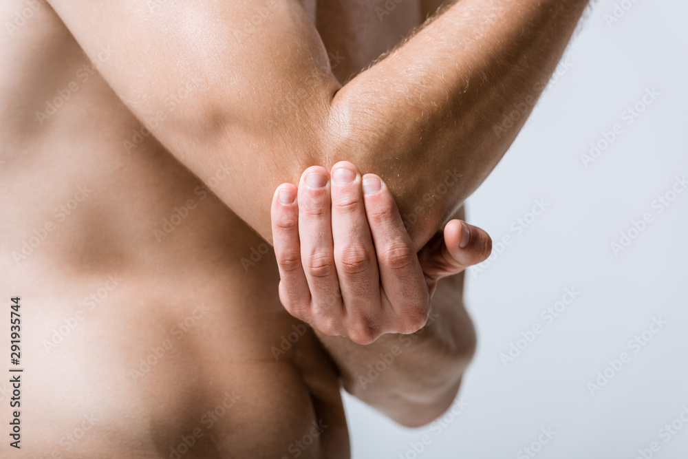 partial view of sportsman with elbow pain isolated on grey partial view of sportsman with elbow pain isolated on grey