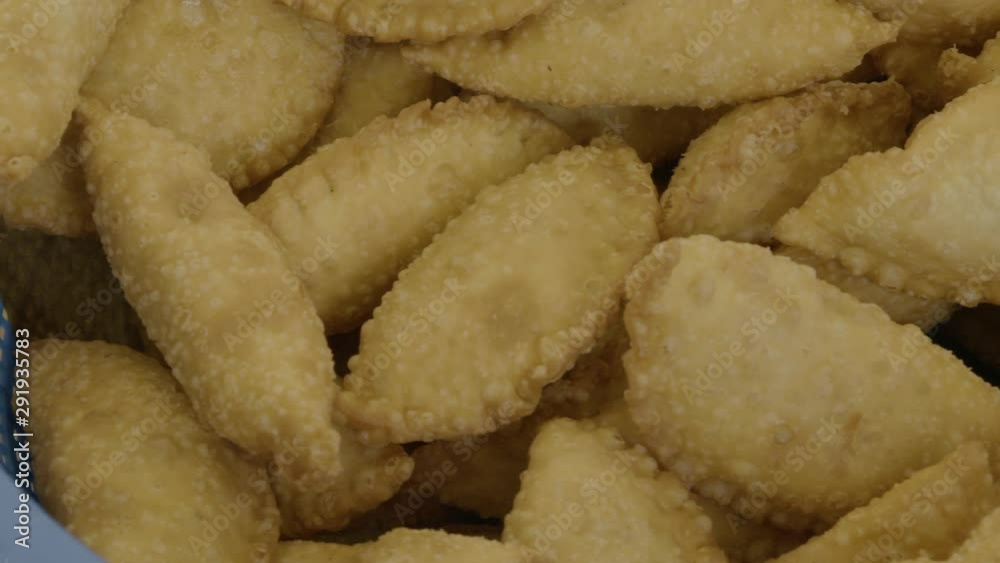 A daylight extreme closeup shot of Vietnamese-style pillow-shape deep-fried dough crispy dumplings (Banh Goi) being removed from the boiling oil using a large strainer.. A daylight extreme closeup shot of Vietnamese-style pillow-shape deep-fried dough crispy dumplings (Banh Goi) being removed from the boiling oil using a large strainer..