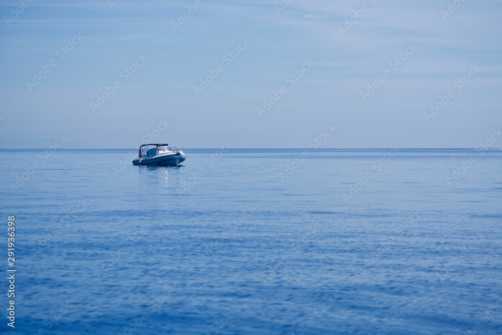 Fisherman on a rubber boat on the blue sea