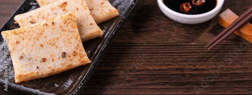 Delicious turnip cake, Chinese traditional local dish radish cake in restaurant with soy sauce and chopsticks, close up, copy space. photo