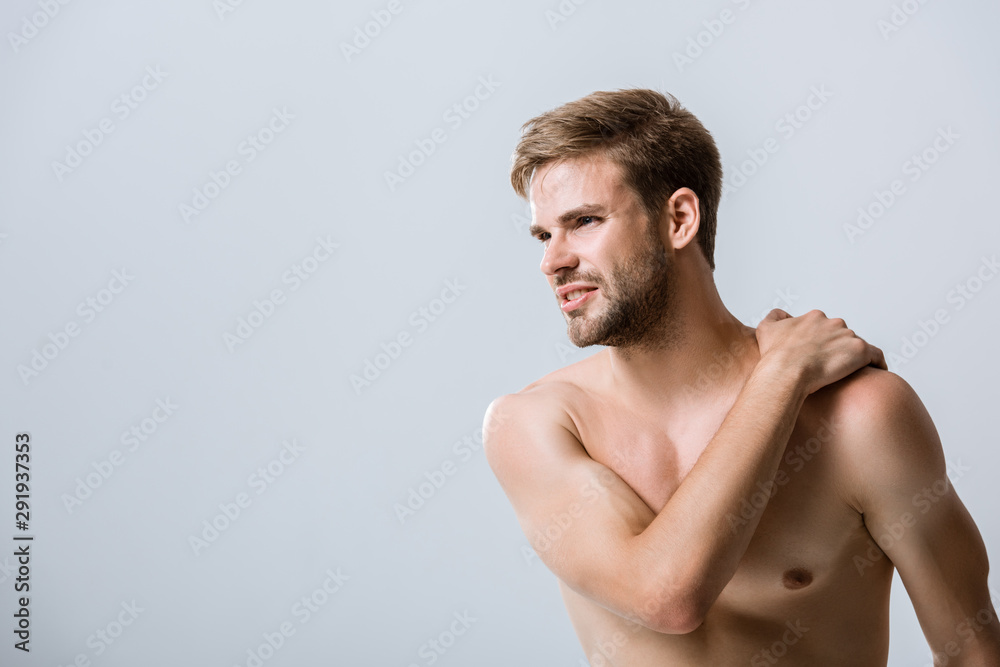 shirtless bearded man with pain in shoulder isolated on grey shirtless bearded man with pain in shoulder isolated on grey