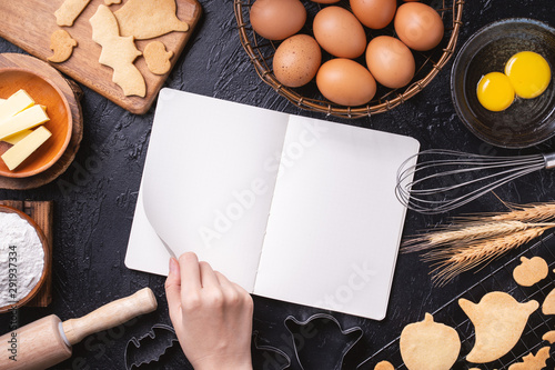 Canvastavla Woman is reading cookbook recipe of making Halloween cookies with baking ingredients, design concept of cooking class, top view, flat lay, overhead
