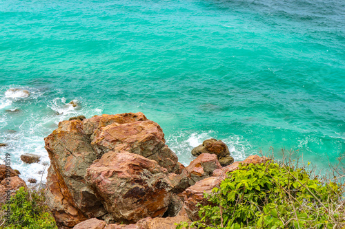 Natural stone beach with splashing wave sea on sunny day at the island.