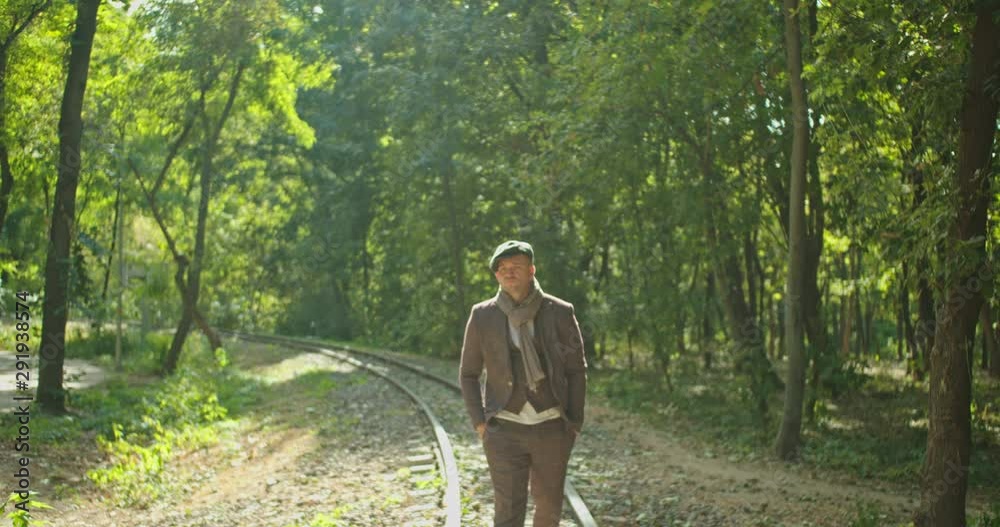 Happy young European man dancing on the rails in forest location . Happy young European man dancing on the rails in forest location .