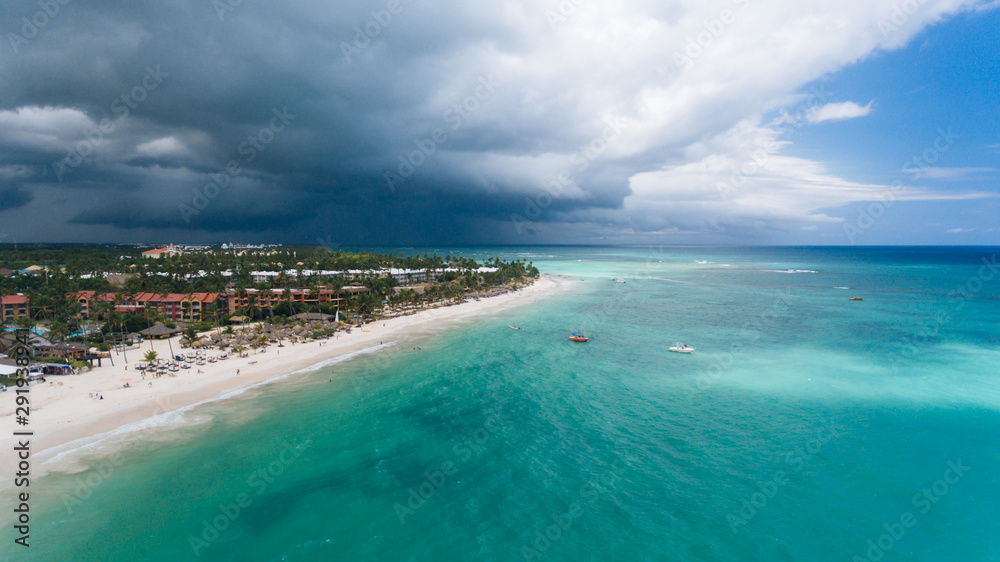 stunning panorama of the blue sea and yellow sand with palm trees, beautiful green palm trees on the shore, aerial view from a flying drone, shooting from a copter, Punta Cana, Dominican Republic