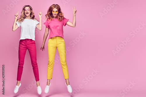 Fashion. Two happy woman laughing jump Having Fun