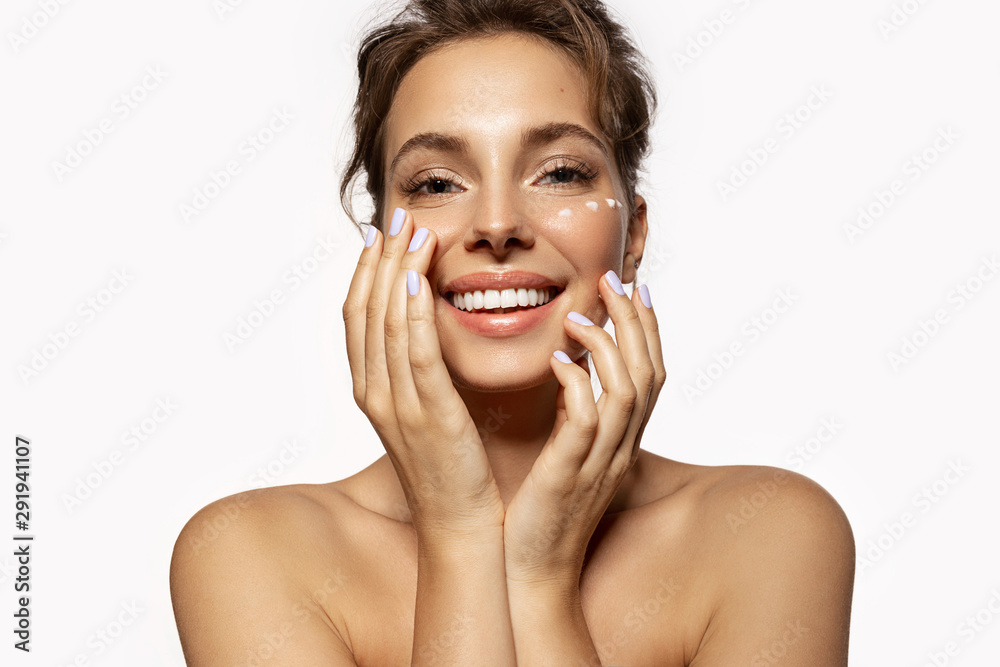 Portrait of beautiful woman applying cream with moisturizing effect. Wonderful female with bare shoulders relaxing spa treatments. Beauty and skincare concept. Isolated on white Portrait of beautiful woman applying cream with moisturizing effect. Wonderful female with bare shoulders relaxing spa treatments. Beauty and skincare concept. Isolated on white