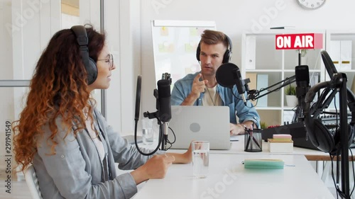 Lockdown of male Caucasian radio host having discussion on air with female redheaded interlocutor sitting nearby in studio photo