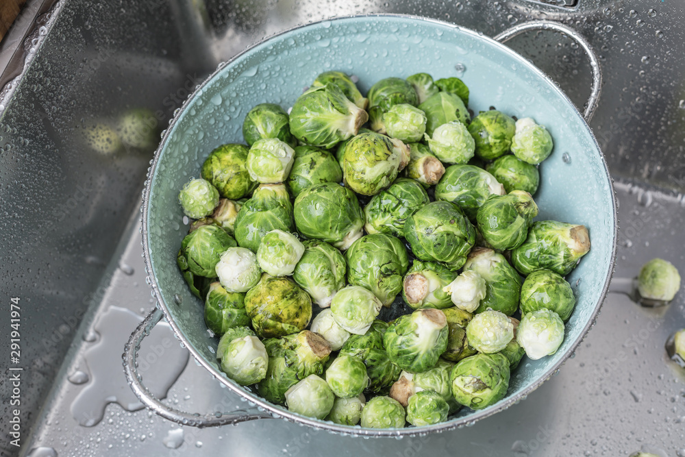washing raw Brussels sprouts in kitchen sink washing raw Brussels sprouts in kitchen sink