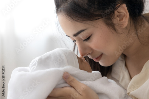 Close up asian young mother kissing her cute newborn baby. Wife and mother's day concept.