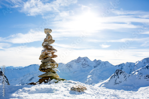 Pile of rocks on top of the mountain on sunset, snow and blue sky © Tomsickova