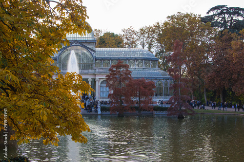 A beautiful view of a crystal building known as the crystal palace and a pond in a park of the city of Madrid in fall season 