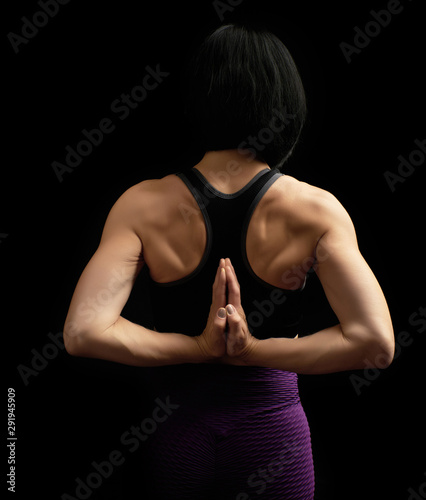 young woman with a sports figure and muscles joined her hands behind her back