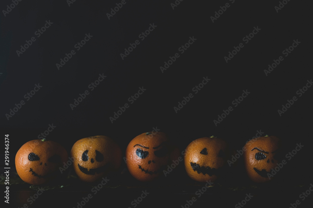 Happy Halloween citrus, tangerines painted with scary, funny faces. Dark photo with copy space. Happy Halloween citrus, tangerines painted with scary, funny faces. Dark photo with copy space.