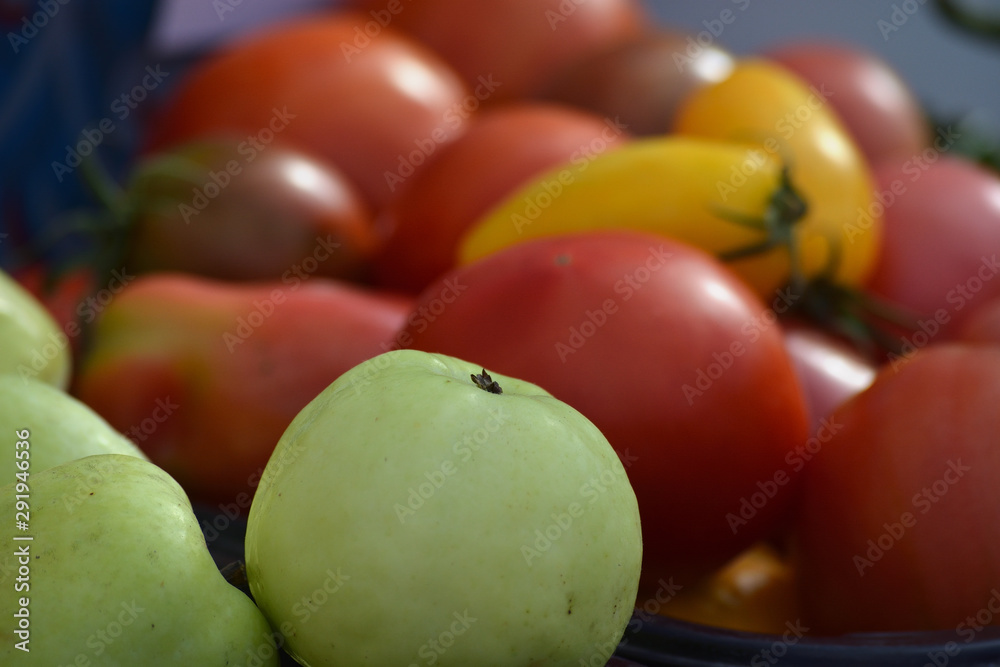 Green apple on a background of red and yellow tomatoes. Autumn harvest Green apple on a background of red and yellow tomatoes. Autumn harvest