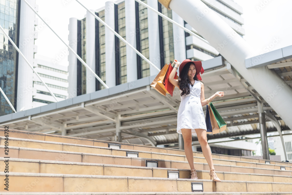 Beautiful woman in white dress holding shopping bags in city.