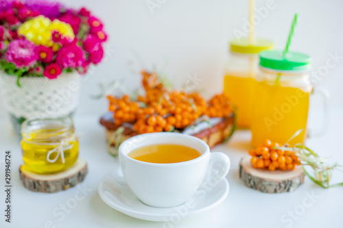White background  natural lighting. Warm sweet organic tea with sea buckthorn berries  thyme and honey.