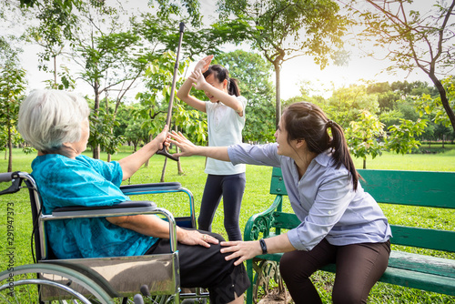 Asian teenager girl hands up to prevent grandmother’s hit,elderly grandma holding walking stick in hand,angry senior is hit the naughty granddaughter,bad child behaviour in park,family 