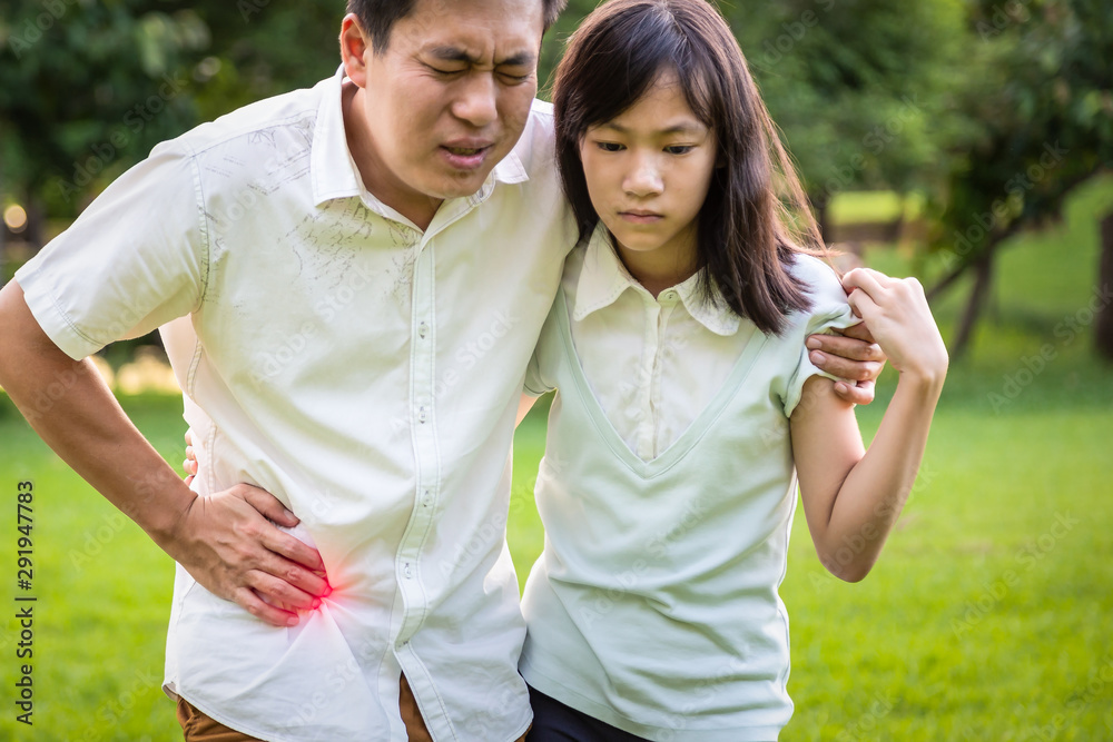 Asian man stomach painful in the right side attack of appendicitis with daughter help care support his father suffering from stomachache in park feeling acute pain,appendicitis ,healt care concept