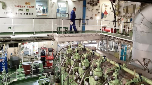 professional engineer walks on special upper ground with handrails over large ship engine room equipment