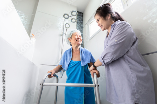 Asian daughter or female care assistant service, help,support senior woman taking a shower in bathroom,care closely,happy mother walking with walker in bathroom at home,safety of elderly people 
