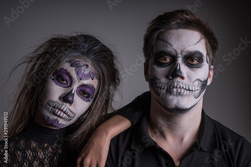 A guy and a girl with painted scary Ghost masks on their faces in honor of Halloween