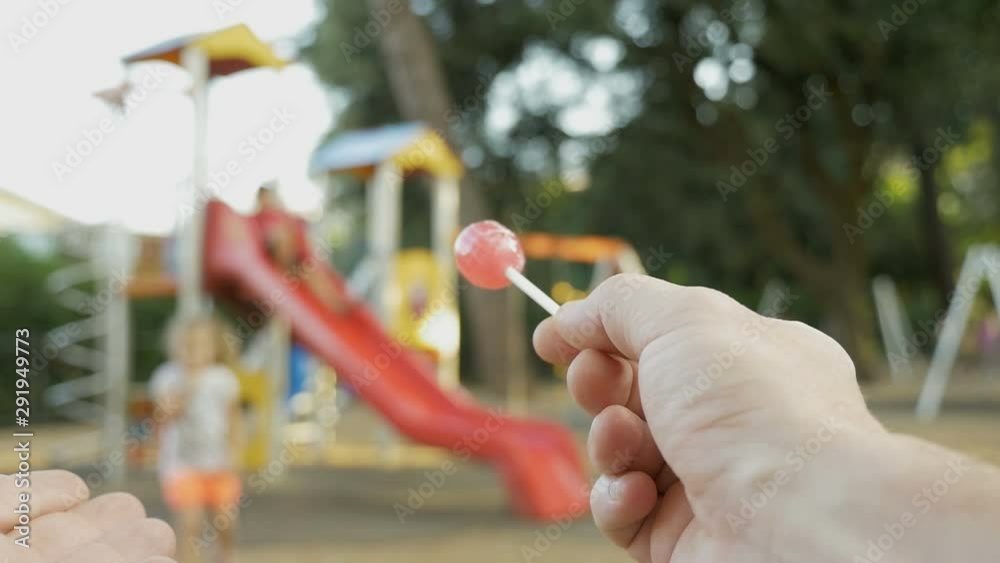 Attempt of child abduction. Stranger with candy in hand tries to theft a child. Person spying on kids on the playground and calls a child to himself. Child abduction, human kidnapping concept. Attempt of child abduction. Stranger with candy in hand tries to theft a child. Person spying on kids on the playground and calls a child to himself. Child abduction, human kidnapping concept.