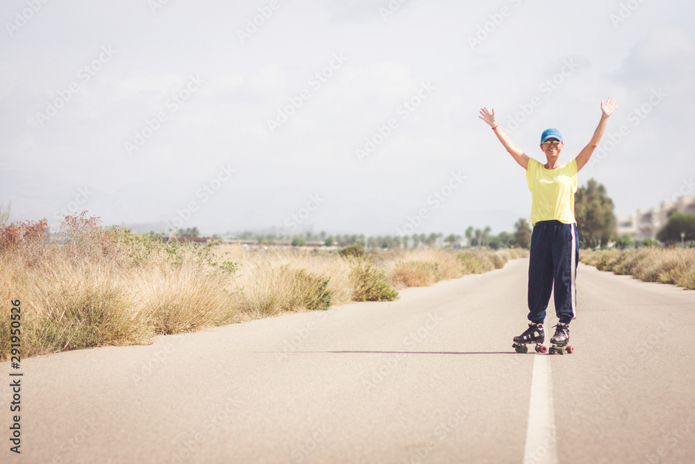 A skater raises her arms and smiles at the camera. Desert landscape