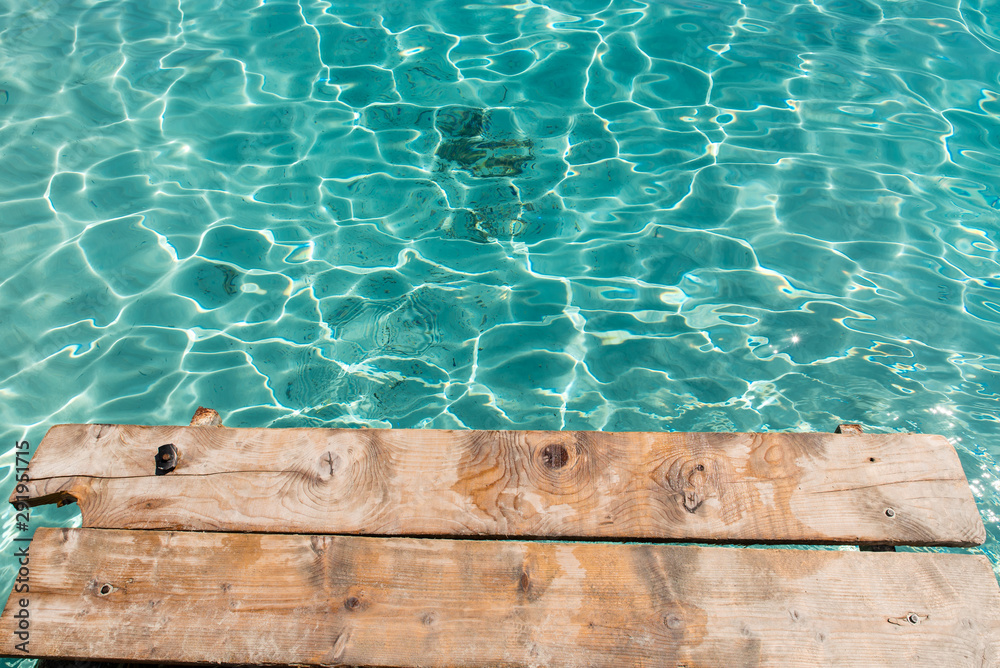 A crystal clear waters from the small wooden pier in the Voutoumi beach in the island of Antipaxoi, Ionian islands, Greece