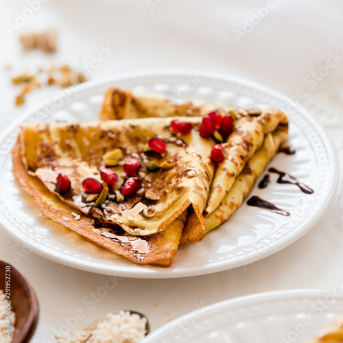 Thin Crepes with melted chocolate, sesame seeds, pomegranate and almonds. Top view. Tasty thin pancakes