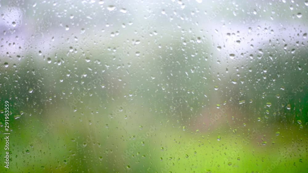 Drops Of Rain on window glass with blur background slow motion