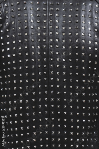 Back of a black leather jacket with metal rivets. Biker or punk studded style. Sample of stylish clothing products. Textured background. Fashionable rocker clothes. Vertical photo.
