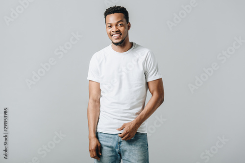 African American man in white T-short smiling and looking at camera isolated on grey