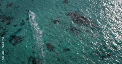 Aerial shot of kitesurfer in riding waves with water splash in a blue sea on a sunny day.