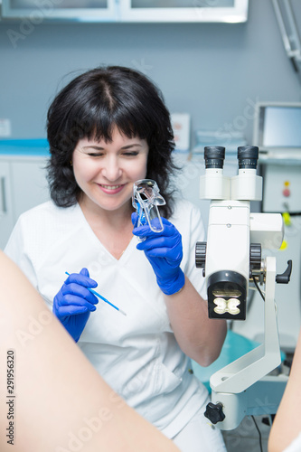 Valokuva woman in a white coat and blue gloves doctor gynecologist examines a patient on